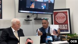 Rolando Cartaya, de la Fundación para los Derechos Humanos en Cuba (izq.), escucha a Samuel Rodríguez denunciar a la jueza Melody González como una represora del régimen de La Habana, este martes 27 de agosto de 2024 durante una conferencia de prensa.