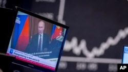 El presidente ruso, Vladimir Putin, aparece en un televisor en la bolsa de valores de Frankfurt, Alemania, el 25 de febrero de 2022, con el titular "Guerra de propaganda en línea y en televisión".