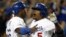 El jugador de los Dodgers de Los Ángeles, el dominicano Juan Uribe (d), es felicitado por su compañero de equipo, el cubano Yasiel Puig (i) después de batear un imparable e impulsar dos carreras contra los Bravos de Atlanta, el lunes 7 de octubre de 2013.