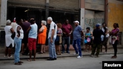 Cubanos hace fila para comprar pollo en una tienda subsidiada o "bodega" en La Habana.
