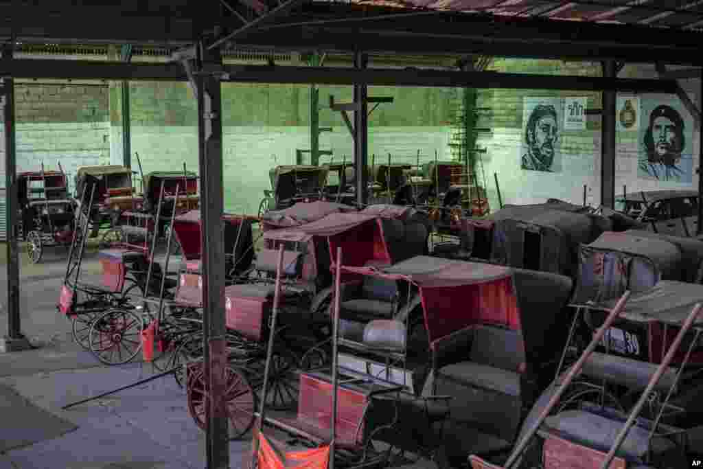 Los carros de caballos que solían dar paseos a los turistas permanecen inactivos en el garaje de una cooperativa donde los murales del difunto líder Fidel Castro y el héroe revolucionario Ernesto "Che" Guevara cubren las paredes en La Habana, Cuba, el 24 de febrero de 2021.