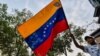 A Venezuelan holds a national flag during a protest against the government of President Nicolas Maduro at Santander square in Cucuta, Colombia, border with Venezuela, on February 12, 2019. - The tug of war between the Venezuelan government and opposition