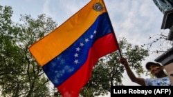 A Venezuelan holds a national flag during a protest against the government of President Nicolas Maduro at Santander square in Cucuta, Colombia, border with Venezuela, on February 12, 2019. - The tug of war between the Venezuelan government and opposition