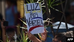 Una mujer pide en un cartel "Luz para Venezuela" durante una marcha de la oposición este 27 de marzo.