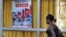 Una joven cubana camina junto a un cartel alusivo a los líderes de la revolución cubana, Fidel y Raúl Castro.