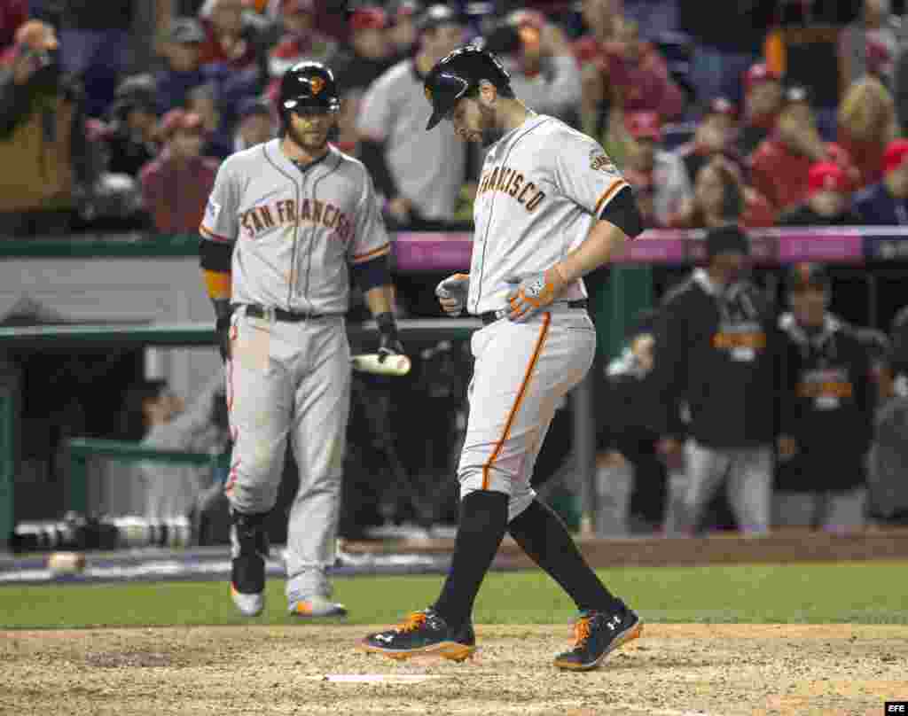 Brandon Belt (d) de los Gigantes de San Francisco llega al plato para anotar la carrera del triunfo en la 18 entrada.