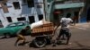 Residentes transportan bloques en una carretilla por una calle de la La Habana.