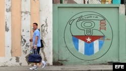 Una pareja camina junto a un cartel con el emblema de los Comités de Defensa de la Revolución (CDR), en La Habana, Cuba.