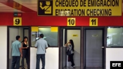 Dos mujeres chequean su pasaportes en las cabinas de emigración del aeropuerto Internacional José Martí hoy, martes 16 de octubre de 2012, en La Habana (Cuba). Cuba anunció hoy la eliminación de los permisos de salida para viajar al extranjero y dejará s