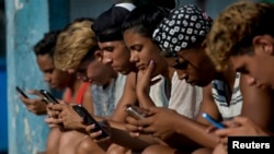 Jóvenes cubanos se conectan a internet desde su teléfono móvil en La Habana.