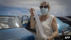 Cubana enseña el comprobante de ventas tras comprar en una tienda en La Habana donde pagó con una tarjeta magnética respaldada en dólares.