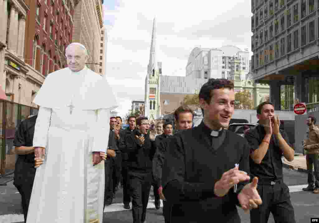 Seminaristas católicos marchan por las calles de Filadelfia junto a una imagen gigante del Papa.