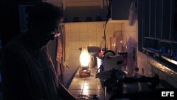 Una mujer lava los platos iluminada por una lámpara de queroseno en el habanero barrio de El Vedado. EFE