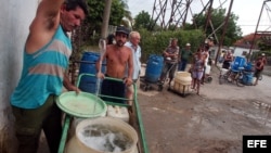 Varias personas con cubos y tanques hacen cola en un "Punto de agua" del barrio Alcides Pino, Holguín