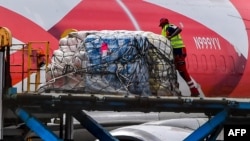 Un trabahjador descarga paquetes de ayuda humanitaria para venezolanos en el Aeropuerto Internacional Hato, en Willemstad, Curazao.