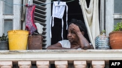 Una mujer mira a la calle desde su balcón en La Habana.