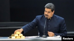 Nicolás Maduro toca una barra de oro mientras se dirige a los ministros responsables del sector económico en el Palacio de Miraflores.