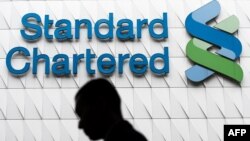 Un hombre pasa frente a las oficinas del Standard Chartered Bank en Hong Kong.